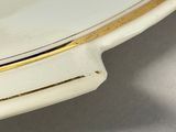 a white plate with a gold edge on a table