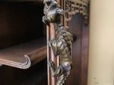 a wooden shelf with a metal dragon handle on it