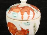 an orange and white bowl with fish on it on a black surface