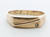une bague en or sertie d'un diamant, posée sur une surface blanche