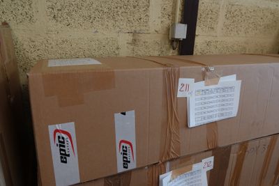 une pile de cartons posée par terre près d'un mur de briques