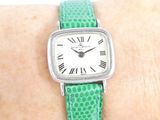 a woman wearing a watch on her wrist with roman numerals on it