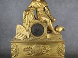 une horloge en or surmontée d'une statue représentant un homme tenant un ballon de football