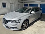une voiture argentée garée dans un garage dont la porte est bleue