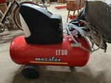 a red air compressor sitting on the floor in a garage