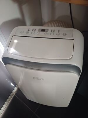 a small white air conditioner sitting on a tiled floor