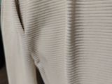 a close up of a white sweater hanging on a hanger