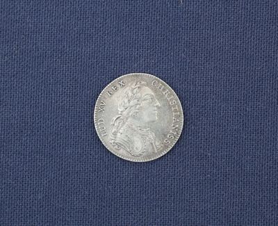 un gros plan d'une pièce d'argent posée sur un tissu bleu