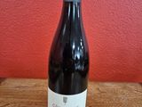 La bouteille de vin est posée sur la table, devant un mur rouge.