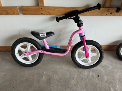 un tricycle rose à côté d'un tricycle noir et blanc