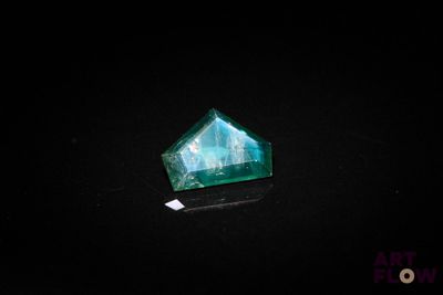 a close up of a green emerald stone on a black surface