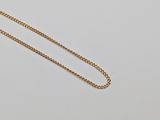 a close up of a necklace with a gold chain on a white surface