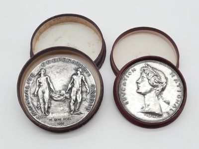 deux pièces d'argent dans une boîte en bois posée sur une surface blanche