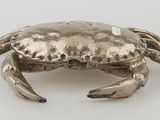 an image of a silver crab sitting on top of a white surface