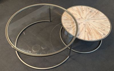 two round coffee tables with glass tops on a black surface