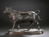 statue en bronze représentant un taureau, posée sur un socle en bois, sur fond noir