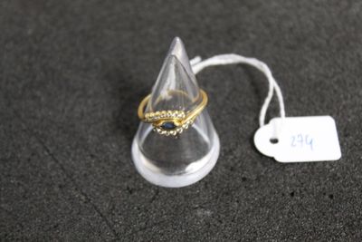 une bague en or posée sur un présentoir transparent, à côté d'une étiquette de prix