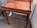 a small wooden table with a glass top on a tiled floor