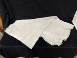 deux morceaux de dentelle blanche posés sur un tissu noir, posé sur une chaise