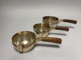 three metal measuring cups with wooden handles on a white surface