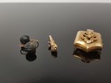 trois bijoux en or et en argent posés sur un fond noir