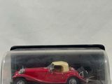 a red model car in a glass case on a white surface