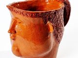 a brown vase with a face on it on a white surface