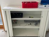 a white cabinet with a red bin on top of it