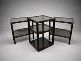 trois tables d'appoint en métal noir et en verre sur fond blanc