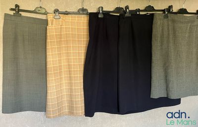 trois paires de pantalons suspendues à un portant devant un mur