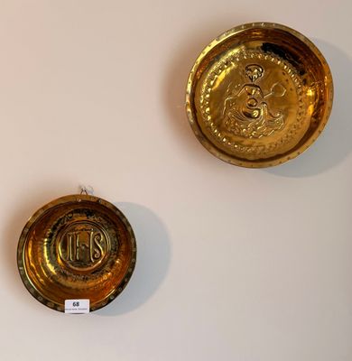 deux plaques dorées accrochées à un mur blanc, auxquelles est attachée une étiquette