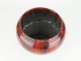 a red and black bowl sitting on a white surface