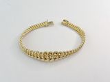 gros plan d'un bracelet en or sur une surface blanche