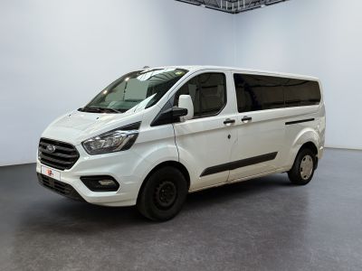 La camionnette blanche est garée dans une grande pièce au sol noir.