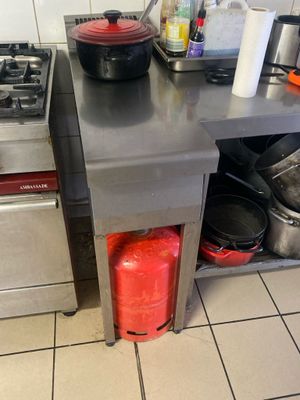 un plan de travail en acier inoxydable sur lequel sont posées des casseroles et des poêles, dans une cuisine professionnelle