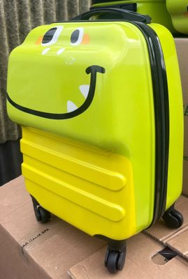 une valise jaune ornée d'un smiley, posée sur une boîte