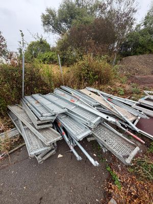 piles of metal and wood sit on the side of a road