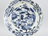 blue and white plate with birds and flowers on a stand