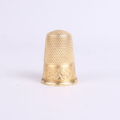 a gold thimble that is sitting on a white surface