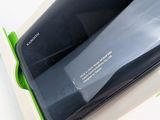 the back of a black samsung phone in a box on a white surface