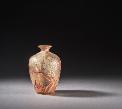 un vase en verre orange posé sur une surface blanche