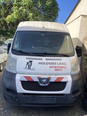 une camionnette blanche garée à côté d'un immeuble sur lequel est accrochée une pancarte