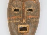 un vieux masque en bois accroché à un mur blanc, sur fond blanc