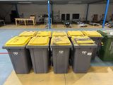 a lot of yellow and gray trash cans in a warehouse