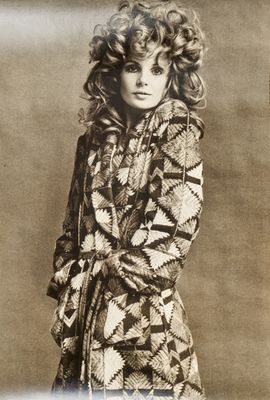 an old photo of a woman with curly hair wearing a coat