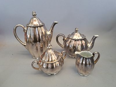 trois théières en argent et un pot à lait posés sur une table