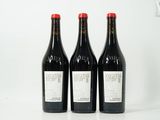 trois bouteilles de vin rouge sont posées sur une surface blanche
