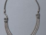 un gros plan d'un collier en argent posé sur une surface grise