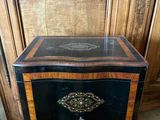 a small black and gold chest on a wooden table