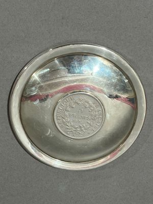un plateau en argent posé sur une table, sur lequel se trouve une pièce de monnaie